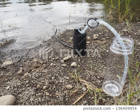 戶外場景:人們在河邊使用便攜式淨水器獲取飲用水。 戶外場景:人們在河邊使用便攜式淨水器獲取飲用水。 136409954