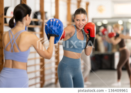 Young girl training boxing kicks on punch mitts 136409961