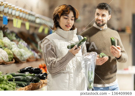 Couple near vegetable stand in store choose zucchini. Couple near vegetable stand in store choose zucchini. 136409969