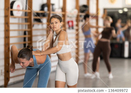 Purposeful engrossed women train during self-defense fight training session in gym Purposeful engrossed women train during self-defense fight training session in gym 136409972