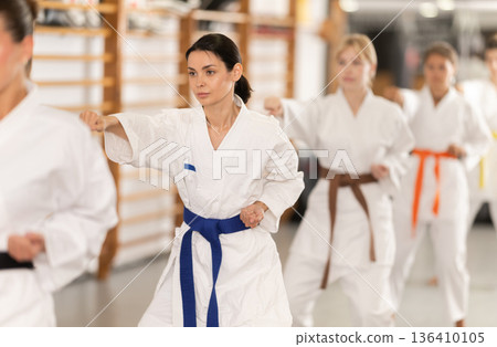 Women students repeat position and perform sequence of punches and painful techniques kata 136410105