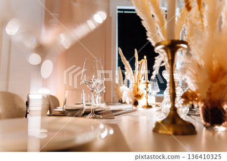Candlelit restaurant table with wine glass, pampas decor and soft bokeh Candlelit restaurant table with wine glass, pampas decor and soft bokeh 136410325