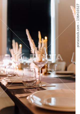 Elegant table setting with lit candle and pampas centerpiece Elegant table setting with lit candle and pampas centerpiece 136410327