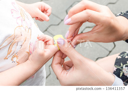 Child healthcare routine. Toddler finger bandaged by mother hands. Daily care concept. Child healthcare routine. Toddler finger bandaged by mother hands. Daily care concept. 136411357