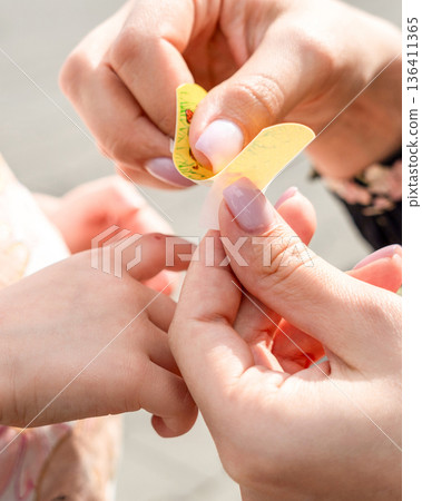 Child first aid. Toddler finger treated by parent hands. Home healthcare concept. Child first aid. Toddler finger treated by parent hands. Home healthcare concept. 136411365