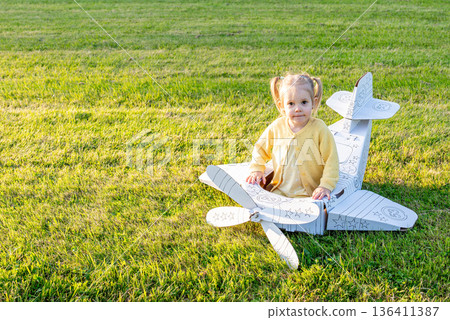 Airplane child. Girl flying cardboard pilot. Outdoor yellow costume grass park. Airplane child. Girl flying cardboard pilot. Outdoor yellow costume grass park. 136411387