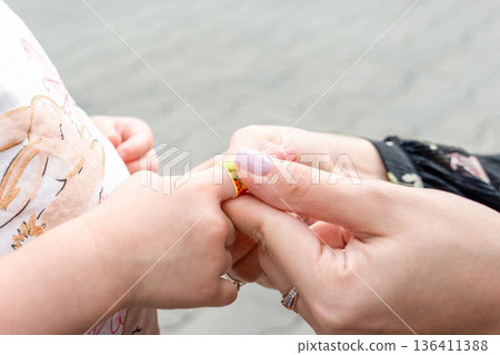 Child finger injury. Toddler receiving adhesive support outdoors. Family wellbeing concept. Child finger injury. Toddler receiving adhesive support outdoors. Family wellbeing concept. 136411388