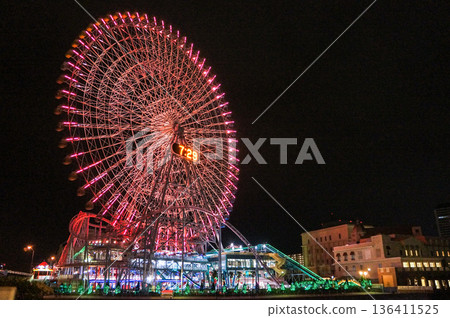 A red glowing Ferris wheel at night and cityscape 136411525