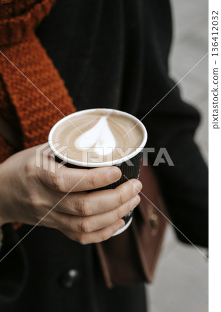 Hand holding a takeaway coffee cup in autumn park background. High quality photo Hand holding a takeaway coffee cup in autumn park background. High quality photo 136412032