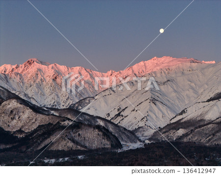 Beautiful morning glow of Mt. Karamatsu and Mt. Goryu and the setting moon of the full moon, Hakuba Village, Nagano Prefecture (aerial shot by drone) 136412947