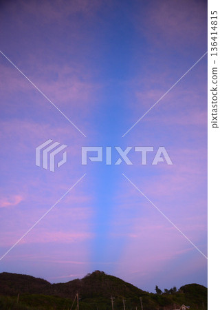 Streaks of light and mountain shadows stretching across the evening sky 136414815