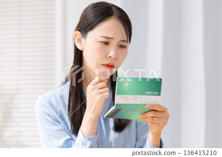 A woman who is worried about looking at her passbook A woman who is worried about looking at her passbook 136415210