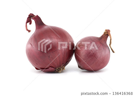 Two vibrant red onions with dry skins sit side-by-side on a clean white background 136416368