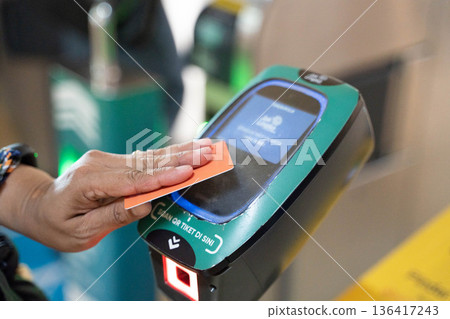 Jakarta: Hand tapping IC card at MRT ticket gate - cashless payment concept Jakarta: Hand tapping IC card at MRT ticket gate - cashless payment concept 136417243