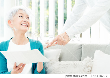 Senior woman looking at documents on the sofa Senior woman looking at documents on the sofa 136418707