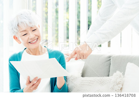 Senior woman looking at documents on the sofa Senior woman looking at documents on the sofa 136418708