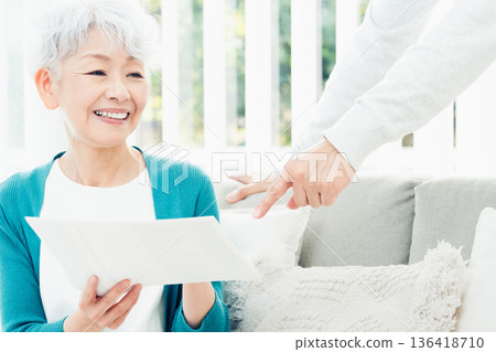 Senior woman looking at documents on the sofa 136418710