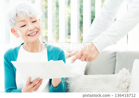 Senior woman looking at documents on the sofa Senior woman looking at documents on the sofa 136418712