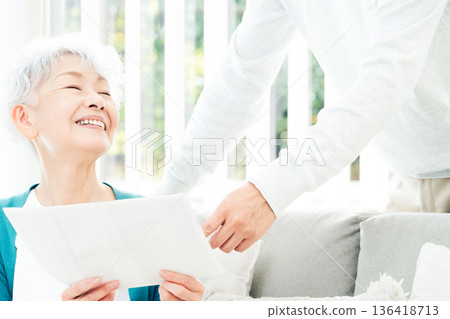 Senior woman looking at documents on the sofa 136418713