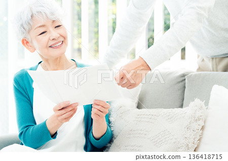 一位老婦人坐在沙發上看文件 136418715
