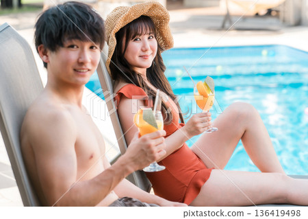 Travel, couple in swimsuits sitting on sun loungers by the pool on vacation Travel, couple in swimsuits sitting on sun loungers by the pool on vacation 136419498