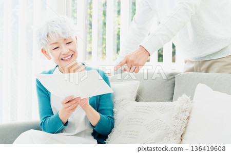 一位老婦人坐在沙發上看文件 136419608