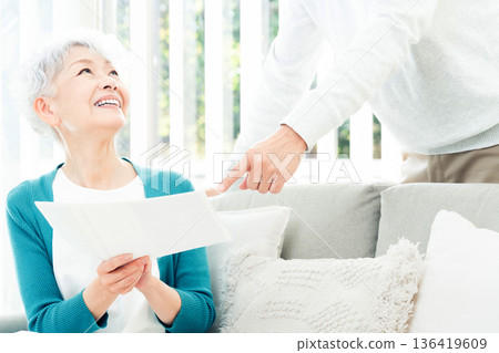 一位老婦人坐在沙發上看文件 136419609