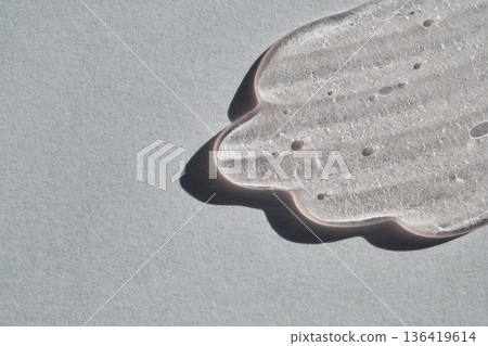Clear skincare serum gel smear on gray background, showcasing texture and air bubbles 136419614