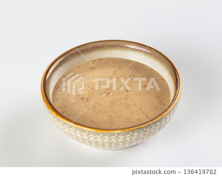 Creamy nut or seed sauce in a decorative ceramic bowl, isolated on a white background. 136419782
