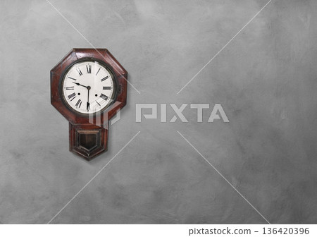An old wall clock on a cement wall. 136420396