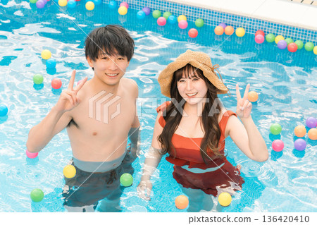 一對年輕的亞洲夫婦在度假勝地的泳池玩耍 136420410