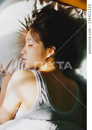 A woman oversleeping in the morning sunshine 136421318