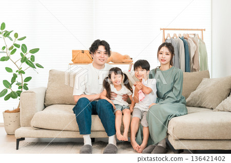 一家四口坐在客廳的沙發上,父母和孩子,一家四口。 一家四口坐在客廳的沙發上,父母和孩子,一家四口。 136421402