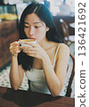 A young woman drinking coffee at a coffee shop 136421692