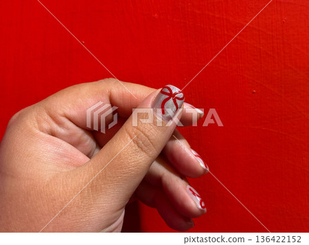 Female hand with red bow nail art on silver manicure background 136422152