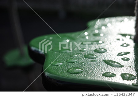 Close-up of raindrops on a wet park bench after rainfall. Atmospheric image with shallow depth of field, perfect for themes such as weather, loneliness, autumn, melancholy Close-up of raindrops on a wet park bench after rainfall. Atmospheric image with shallow depth of field, perfect for themes such as weather, loneliness, autumn, melancholy 136422347