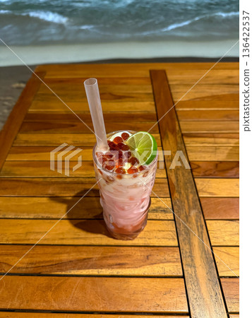 Tropical cocktail with lime on wooden table by sea Tropical cocktail with lime on wooden table by sea 136422537
