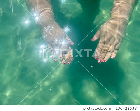 Female hands underwater in clear turquoise sea Female hands underwater in clear turquoise sea 136422538