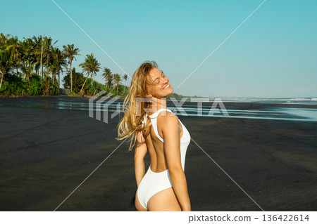 A woman smiles while standing on the beach in Bali A woman smiles while standing on the beach in Bali 136422614