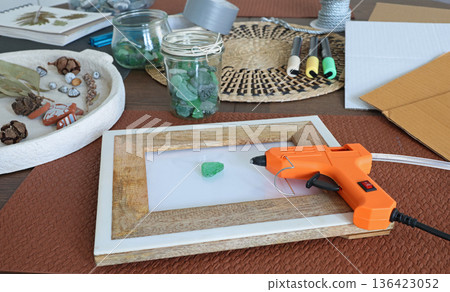 Sea glass in frame. Making art from natural materials. Glue gun and driftwood for picture. Hobbies and creativity. Reuse and nature, ecology. Sea glass in frame. Making art from natural materials. Glue gun and driftwood for picture. Hobbies and creativity. Reuse and nature, ecology. 136423052