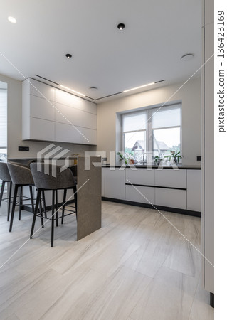Vertical view of modern white kitchen with stone island and stools 136423169