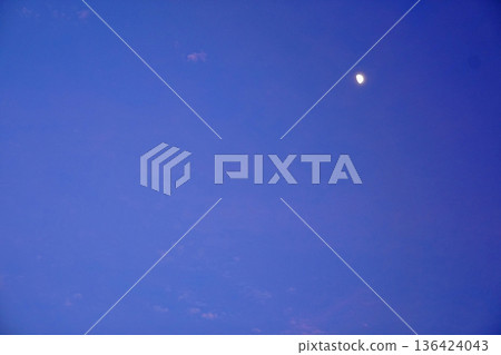 The moon is shining brightly in the sky before dusk, when there is still light remaining. The moon is shining brightly in the sky before dusk, when there is still light remaining. 136424043