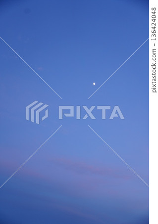 The moon is shining brightly in the sky before dusk, when there is still light remaining. The moon is shining brightly in the sky before dusk, when there is still light remaining. 136424048