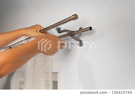 Handyman repairman hanging and fixing the curtain rod on the window Handyman repairman hanging and fixing the curtain rod on the window 136424749