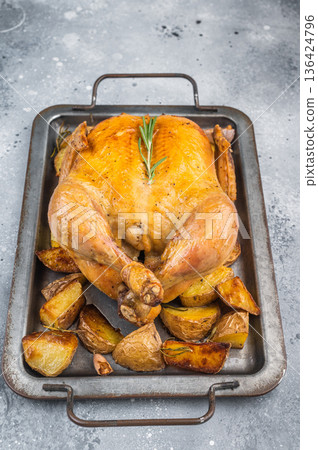 Whole roasted chicken with crispy golden skin baked with potatoes garlic and rosemary served on metal tray Whole roasted chicken with crispy golden skin baked with potatoes garlic and rosemary served on metal tray 136424796