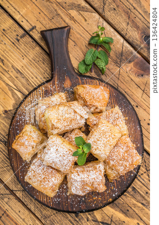 Traditional Greek filo custard pastry also known as milk pie sliced into portions top view bakery dessert 136424804