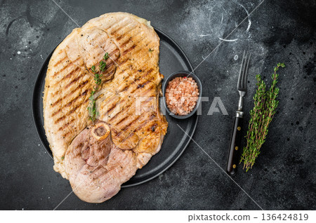 Juicy grilled pork shoulder whole cut with bone on black plate dark background food styling with fresh thyme and spices 136424819