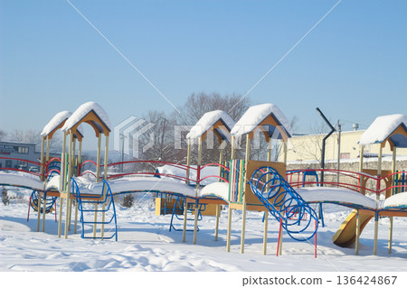 Colorful Children Playground Covered in Thick Snow on Sunny Winter Day 136424867