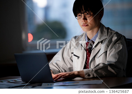 一名身穿工作服的男子正在加班 136425687