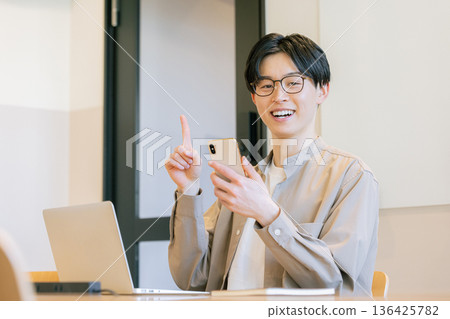 一位戴眼鏡的男子在咖啡館使用智慧型手機。 一位戴眼鏡的男子在咖啡館使用智慧型手機。 136425782